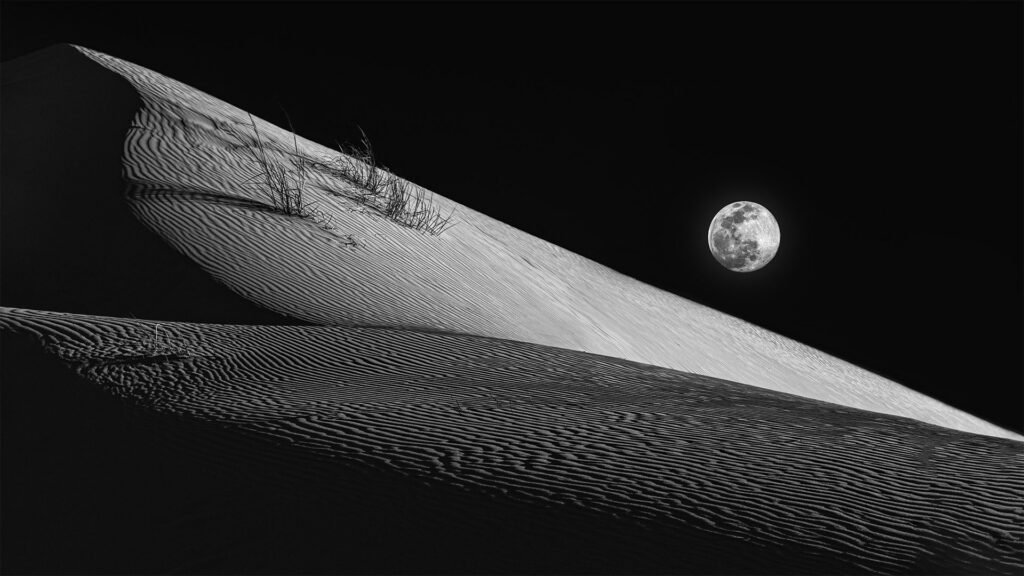 Composite photograph of sand dunes at Monahans Sandhills State Park in Texas, with a full moon added above the dunes for dramatic effect.