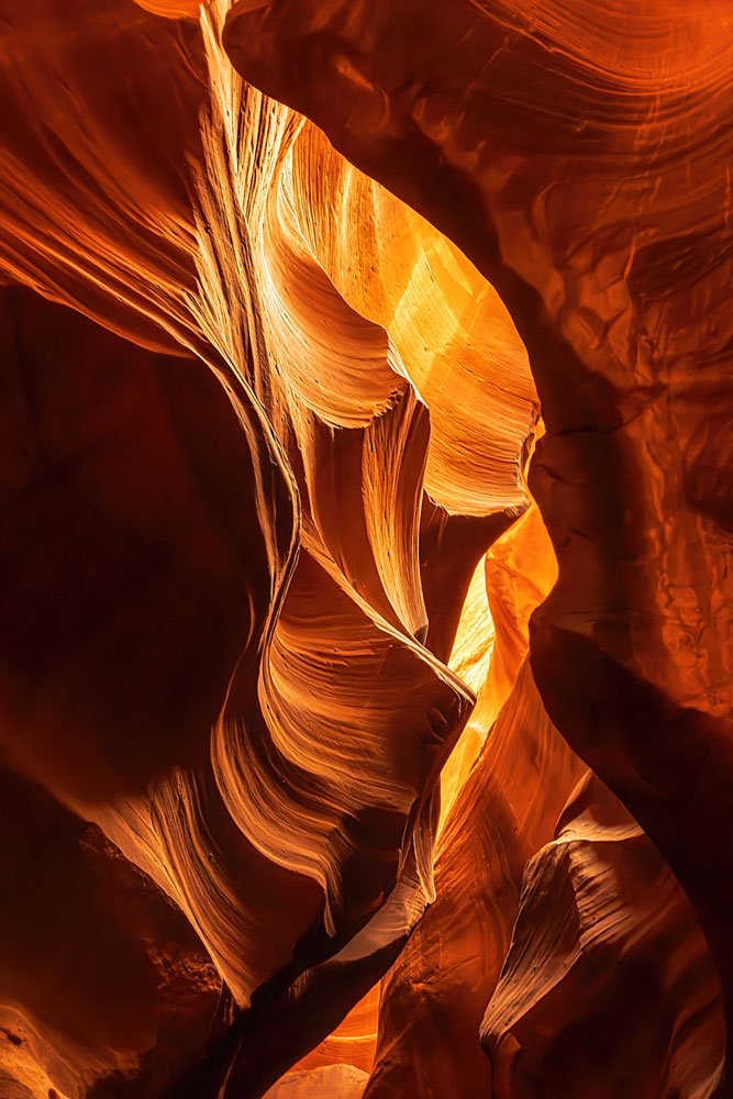 Abstract view inside Upper Antelope Canyon, with warm orange light illuminating the flowing curves and layered textures of the sandstone walls.